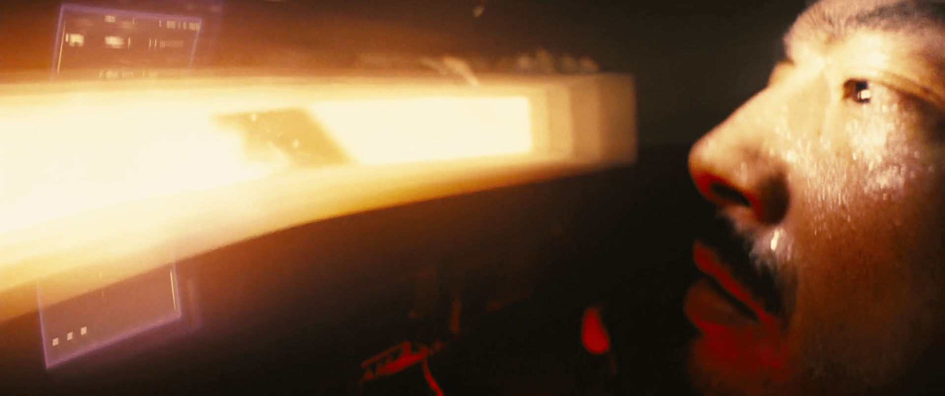 Hiroyuki Sanada, dont on ne voit qu'une partie du visage, voit à travers une fente horizontale de son casque une intense lumière jaune-orangée