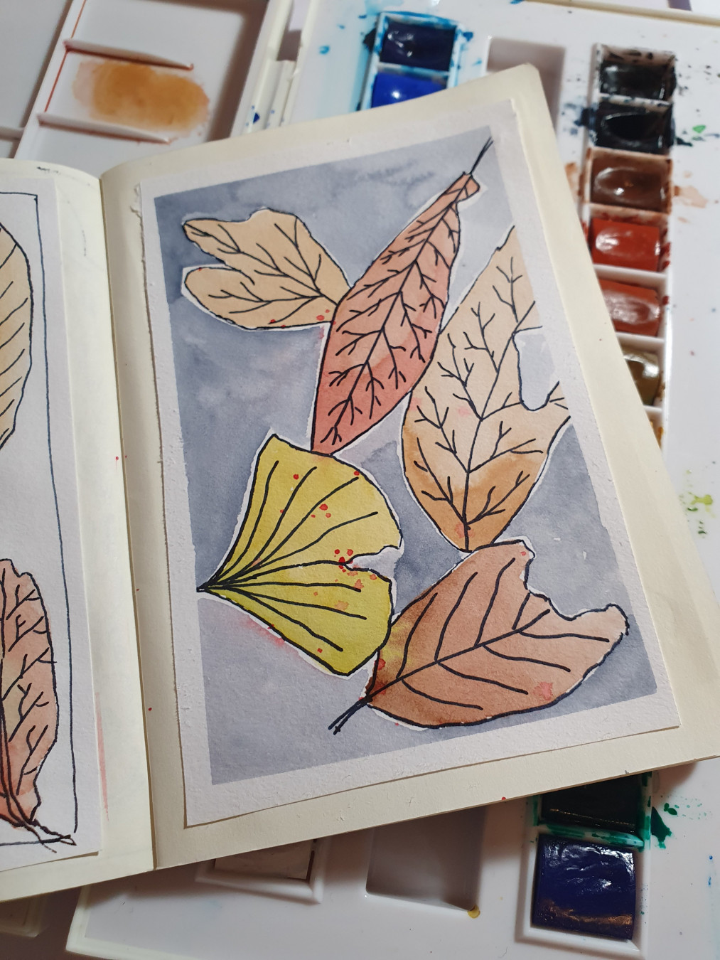 Feuilles mortes à l'aquarelle, tons jaune à brun, sur fond gris.
Contours au stylo plume