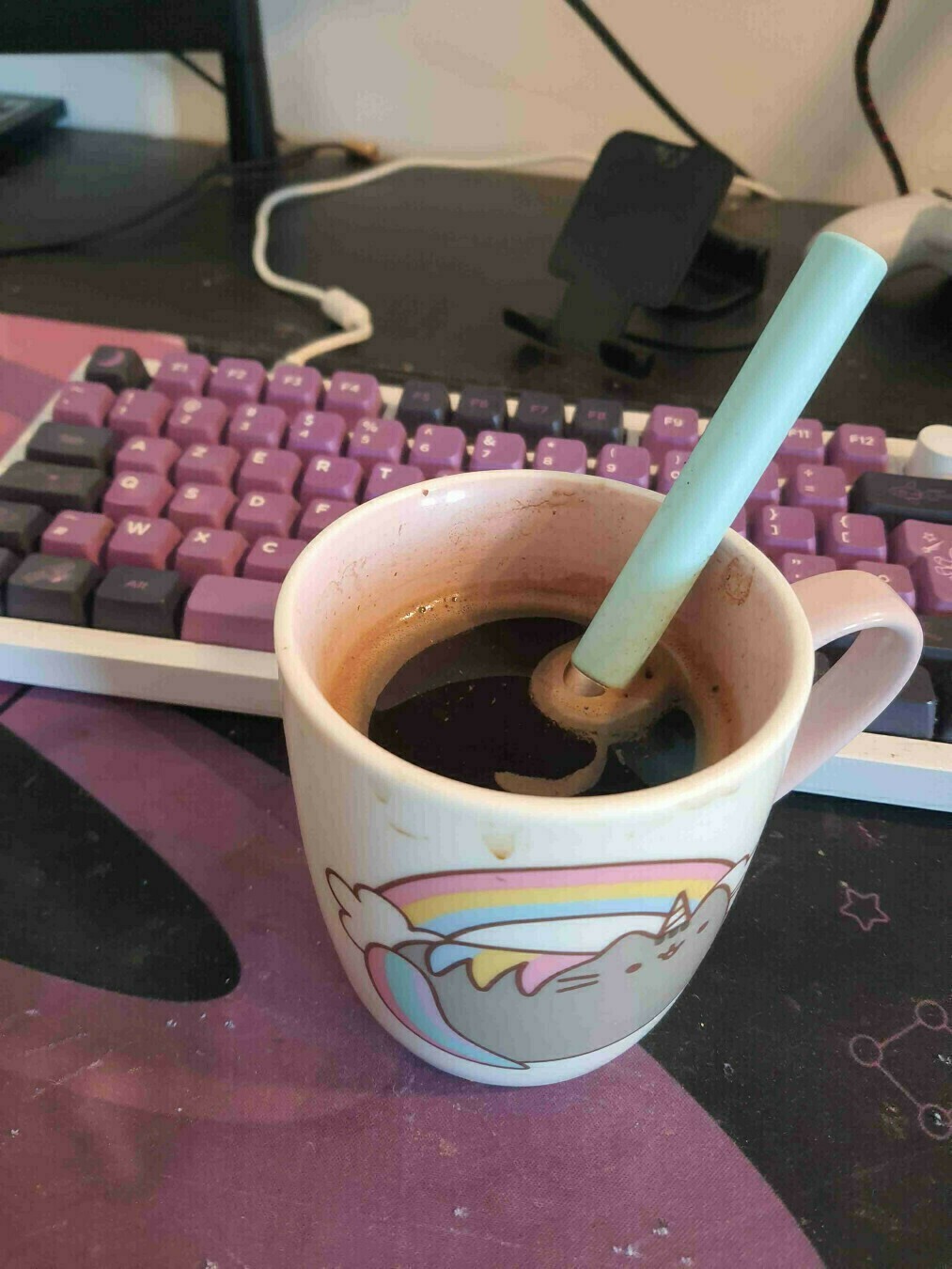 Tasse de café sur un bureau devant un clavier noir et violet