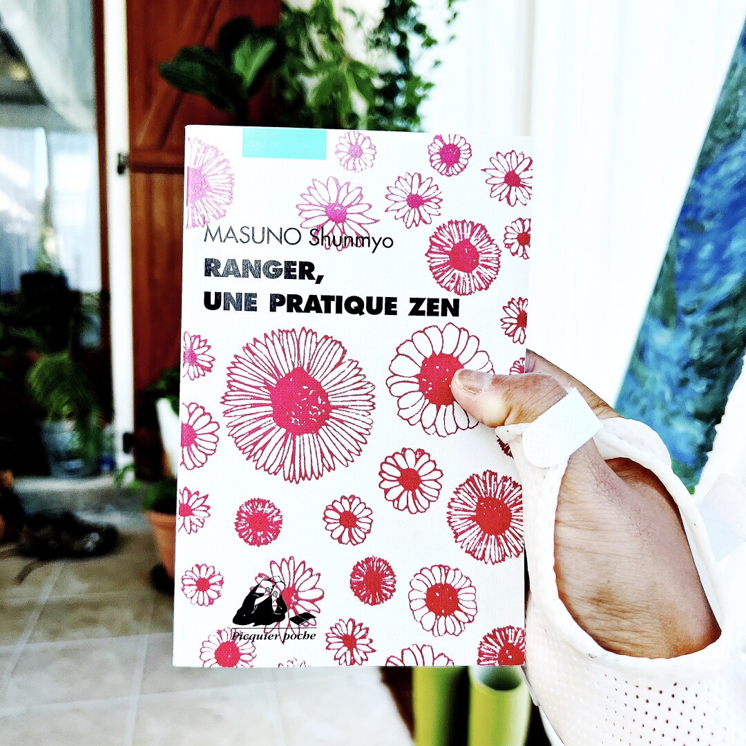J’ai une orthèse à la main à cause d’une tendinite mais je tiens un livre qui s’intitule Ranger une pratique zen de Masuno Shunmyo - la couverture est moderne avec un motif de fleurs rouges et un fond beige