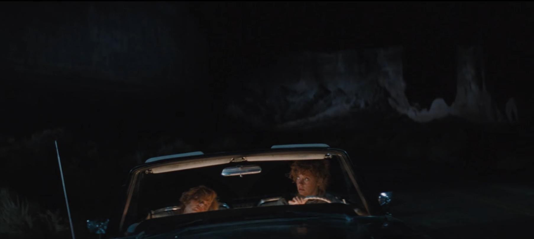 [Image extraite du film "Thelma et Louise" (Ridley Scott, 1991). Dans une voiture décapotable, en pleine nuit, Thelma (Geena Davis) dort sur le siège passager, tandis que Louise (Susan Sarandon) est au volant et regarde à sa droite]