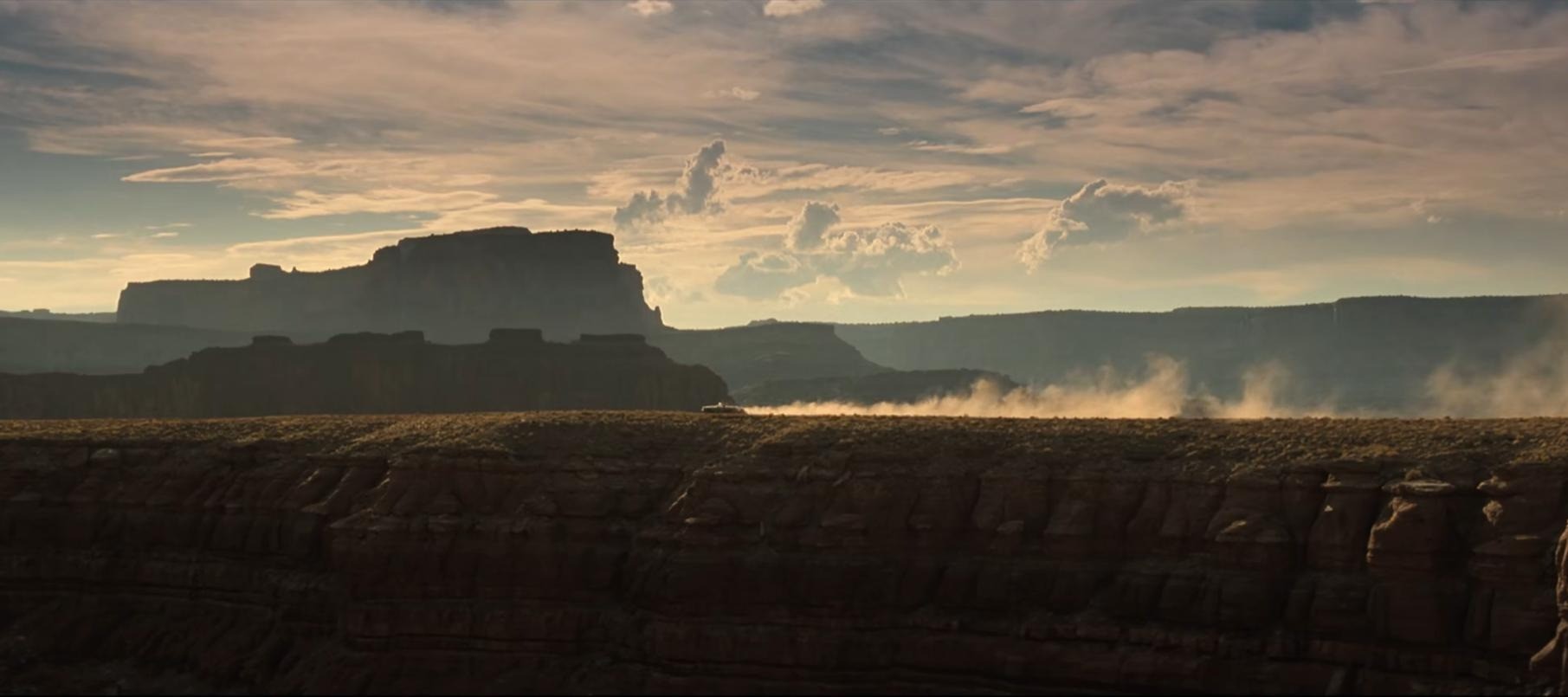 [Image extraite du film "Thelma et Louise" (Ridley Scott, 1991) ; Plan général sur une voiture roulant au sein du Grand Canyon américain, de droite à gauche. Le véhicule déplace de la poussière sur son passage.]